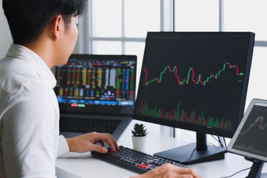 Asian investor looks at charts and graphs on screens