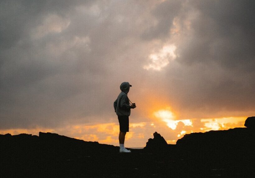 Man standing on rocky terrain at sunset